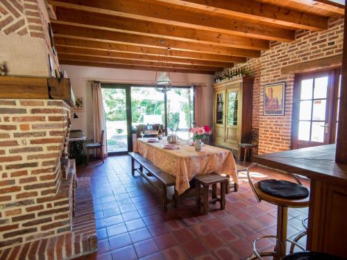 une salle à manger avec une table et un mur de briques dans l'établissement Holiday Home Alexandre by Interhome, à La Chapelle-Saint-Sauveur
