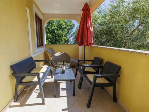 a porch with chairs and a table and an umbrella at Apartment Gabi - MDN152 by Interhome in Ližnjan