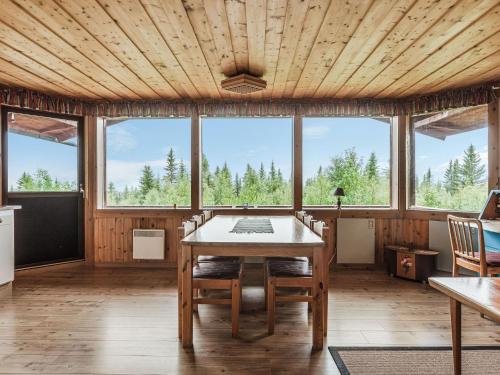 a dining room with a table and chairs and windows at Chalet Högvallen Elden - JAM025 by Interhome in Undersåker