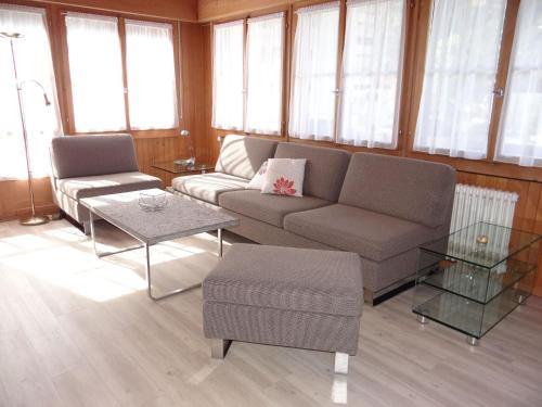 ein Wohnzimmer mit einem Sofa, Tischen und Fenstern in der Unterkunft Apartment Valentine by Interhome in Engelberg