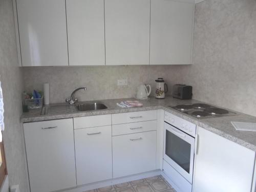 a kitchen with white cabinets and a sink at Apartment Valentine by Interhome in Engelberg