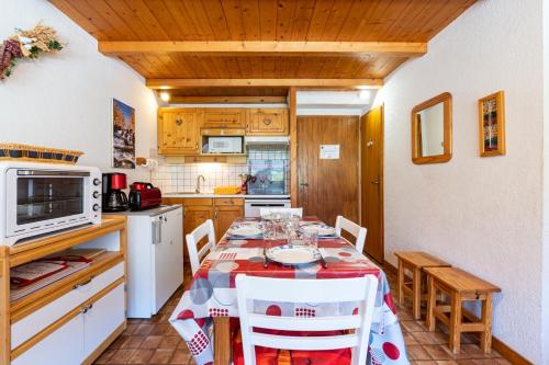 une cuisine avec une table avec des chaises et un micro-ondes dans l'établissement Le Névé, à Crest-Voland