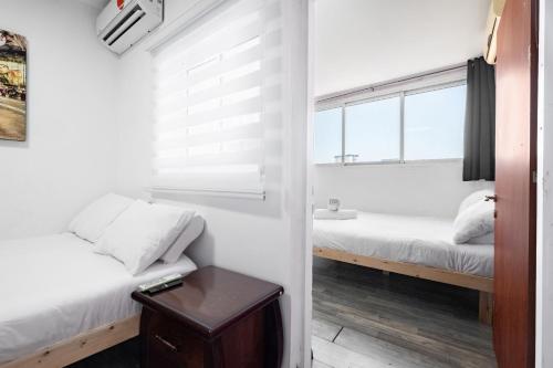 a small room with two beds and a window at relaxing duplex in ashdod by torohome in Ashdod