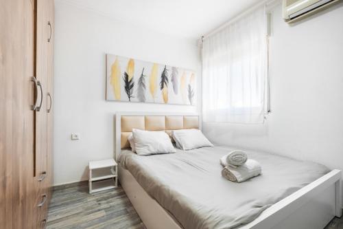 a white bedroom with a bed with a window at relaxing duplex in ashdod by torohome in Ashdod