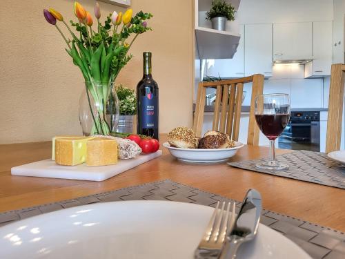 a table with a plate of cheese and a glass of wine at Apartment Caslago-1 by Interhome in Caslano