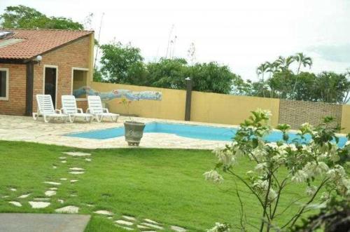 um quintal com piscina e cadeiras e uma casa em POUSADA PEQUIZEIRO em Chapada dos Guimarães