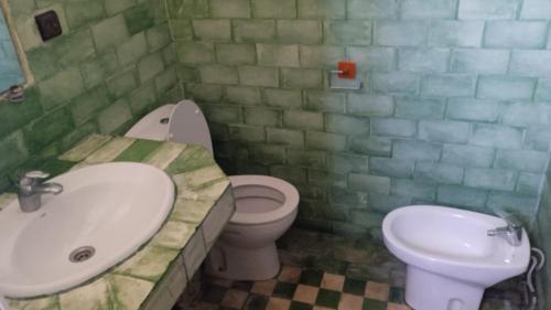 a green tiled bathroom with a sink and a toilet at Soultana 2 pour les familles in Oualidia