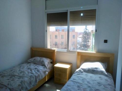 - une chambre avec 2 lits et une fenêtre dans l'établissement Bel Appartement, à Oujda