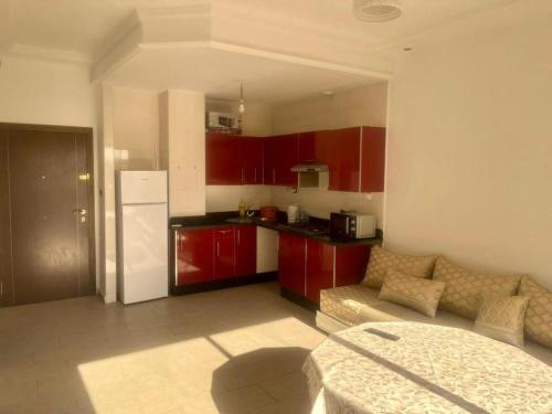 Il comprend une cuisine équipée de placards rouges et d'un réfrigérateur blanc. dans l'établissement Bel Appartement, à Oujda