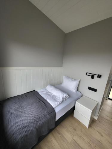 a small bedroom with a bed and a night stand at Landbrot Guesthouse in Kirkjubæjarklaustur