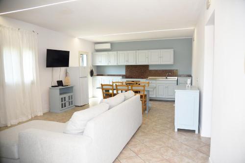 a white living room with a white couch and a kitchen at Beachside House in Sperlonga