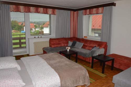 a bedroom with a bed and a couch and windows at Penzion TOMI in Pribylina