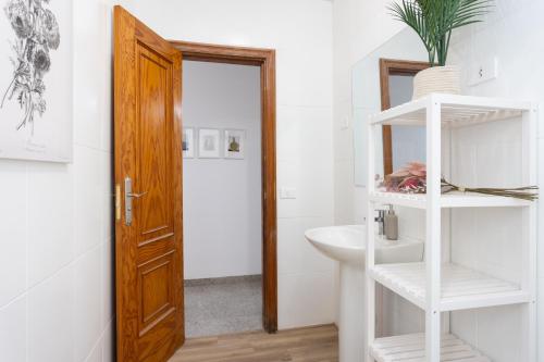 baño con lavabo blanco y puerta de madera en EDEN RENTALS B01 Surfy Stylish Bed&Coffee Room, en Granadilla de Abona