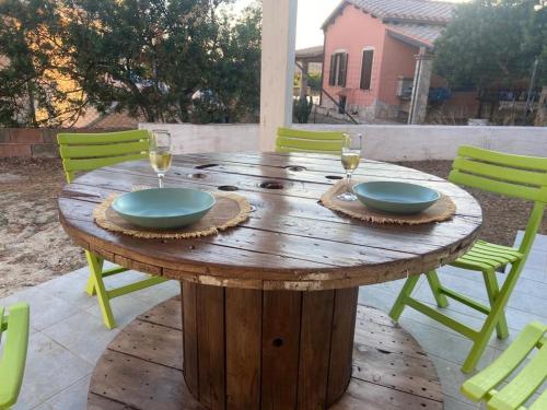 uma mesa de madeira com dois pratos e taças de vinho em Domu Istella em SantʼAnna Arresi