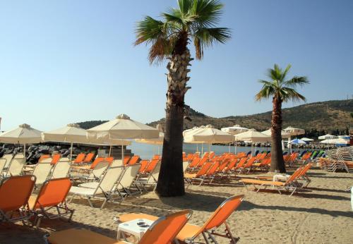 un grupo de sillas y palmeras en una playa en Hotel Stella, en Volos