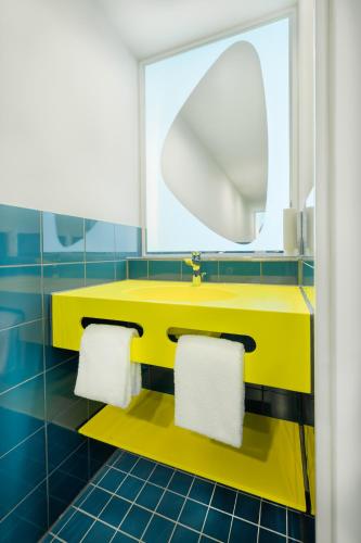 a yellow sink in a bathroom with blue tiles at Prize by Radisson, Dortmund City in Dortmund