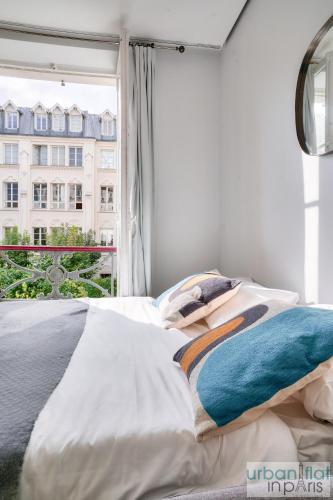 - un lit avec des draps blancs et une fenêtre avec un bâtiment dans l'établissement 127 - Spacious 4BR in Montorgueil, à Paris