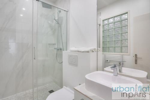 une salle de bain blanche avec une douche et un lavabo dans l'établissement 127 - Spacious 4BR in Montorgueil, à Paris