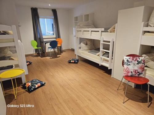 a room with white bunk beds and chairs and wooden floors at Estelada Boarding Houses in Munich