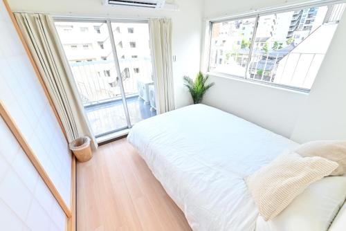 Un dormitorio con una cama blanca y una ventana grande. en 東京 上野 稻荷町3分鐘130平方別墅 6LDK 3 Shower room Ueno Inaricho Private Villa, en Tokio