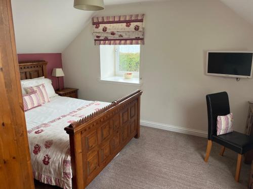 a bedroom with a bed and a tv and a chair at The Dairy in Castle Douglas