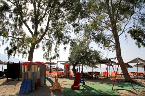 a playground with play equipment and tables and trees at Hotel Stella in Volos