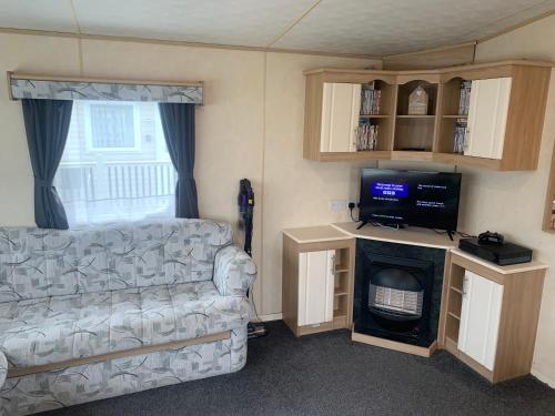a living room with a couch and a flat screen tv at K&Ds Caravans in Chapel Saint Leonards