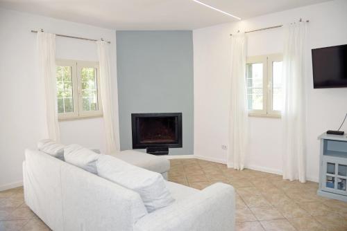a white living room with a white couch and a fireplace at Beachside House in Sperlonga