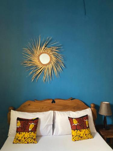 a blue bedroom with a bed with a mirror on the wall at Malaika House Paje in Paje