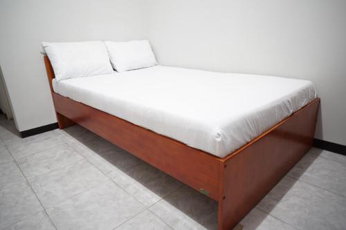 een bed met een houten frame in een kamer bij OYO Life 93045 Kost Putra Bu Ketut in Lumajang