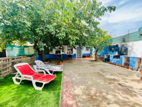 a yard with two chairs and a tree at Estudio adosado acogedor con jardín, barbacoa y parking privado in Alicante