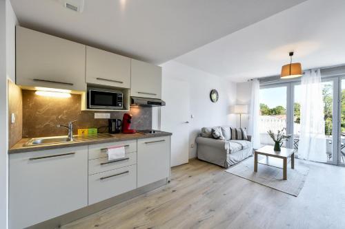 une cuisine avec des armoires blanches et un salon dans l'établissement OVELIA Toulouse - Les Bastides de Lardenne, à Toulouse