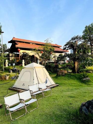 a group of chairs and a tent in the grass at Nhà Vườn Nghĩ Dưỡng Thiên Nhiên in Xã Phước Lợi