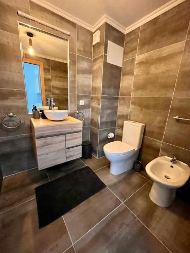ein Badezimmer mit einem WC, einem Waschbecken und einem Spiegel in der Unterkunft Ribeira DIlhas Beach Apartment in Ericeira