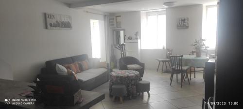 een woonkamer met een bank en een tafel bij Les plaisirs de la ruralité in Vendresse