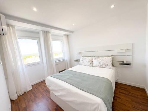 a white bedroom with a large bed and two windows at Plaza España Superb Views in Madrid
