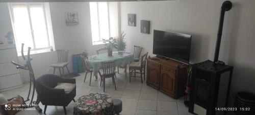 a living room with a table and a television at Les plaisirs de la ruralité in Vendresse