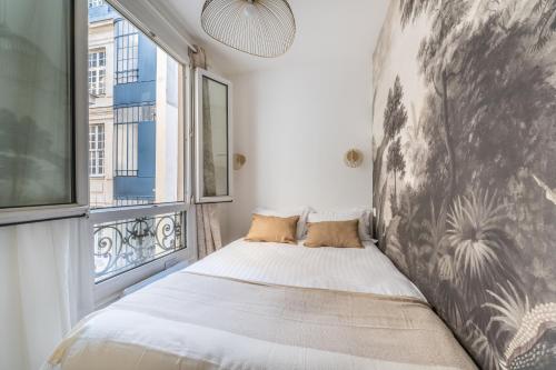 a bed in a room with a large window at Cozy flat Paris centre in Paris