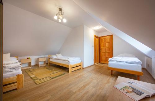 a attic room with two beds and a table at Guest House Mengsdorf in Mengusovce