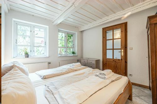 two beds in a white room with two windows at fewo1846 - Altes Steuermannhaus - uriges Reihenhaus mit 2 Schlafzimmern in der Altstadt in Flensburg