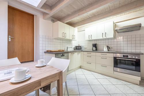 a kitchen with white cabinets and a wooden table at fewo1846 - Altes Steuermannhaus - uriges Reihenhaus mit 2 Schlafzimmern in der Altstadt in Flensburg