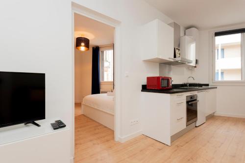 - une cuisine blanche avec un lit et une télévision dans l'établissement Le Bachelier - T2 proches Ramblas de Toulouse, à Toulouse