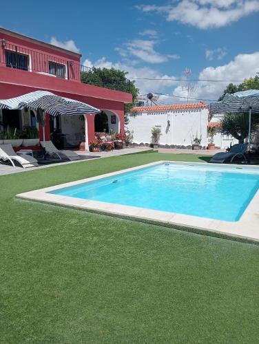 a swimming pool with green grass next to a house at Sunset and oceanview 1 bedroom apartment with shared pool in Salobre