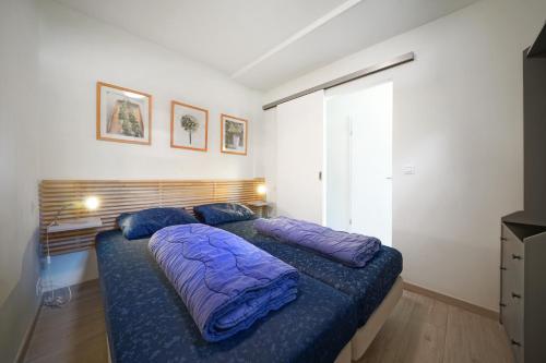 a bedroom with a bed with purple sheets and a window at Domaine Long Pre in Stavelot