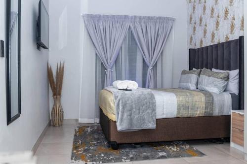 um quarto com uma cama com cortinas roxas e uma janela em Apartments at Brooklyn/Waterkloof em Pretoria