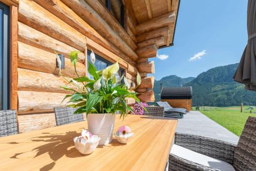 a wooden table with a vase of flowers on a patio at Das Blockhaus Gosau - Your Austrian Home in Gosau