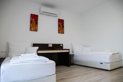 twee bedden in een kamer met witte muren bij Rozmaring Apartmanház in Mórahalom