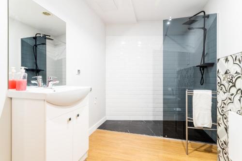 ein weißes Bad mit einem Waschbecken und einer Dusche in der Unterkunft Victus Apartamenty Playa&Relax in Sopot