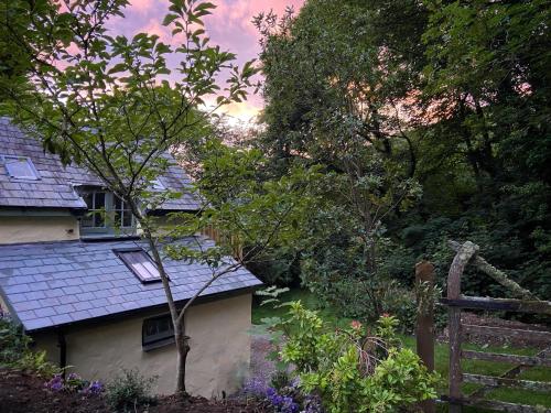 a house with a roof and trees and a fence at The Barley Mill in Bude