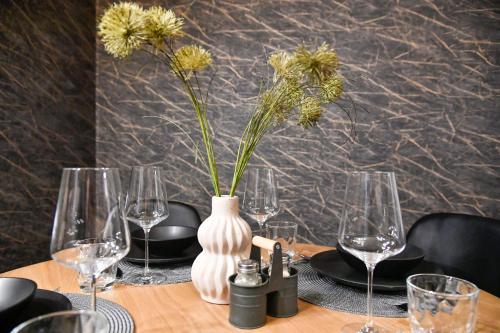 stół z okularami i wazon z kwiatami w obiekcie Exklusives-City-Apartment mit gratis Tiefgarage, Balkon, Waschtrockner, Netflix w mieście Chociebuż